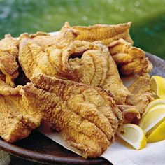 fried fish on a plate with lemon wedges