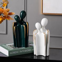 two white and green vases sitting on top of a table