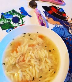 a white bowl filled with pasta and broth sitting on top of a blue plate