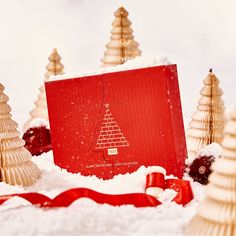 a red box with a christmas tree on it in the snow