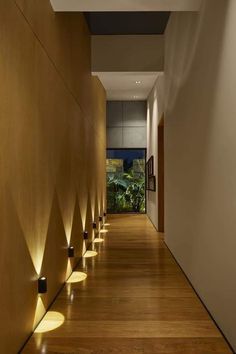 a long hallway with wooden floors and lights on the wall