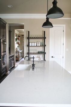 a kitchen with an island sink and hanging lights