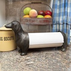 a dog figurine sitting on top of a counter next to a roll of toilet paper