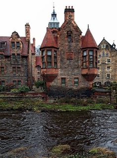 an old brick building sitting next to a river