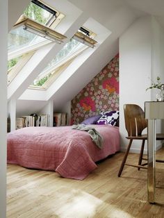 an attic bedroom with pink bedding and floral wallpaper, along with a chair