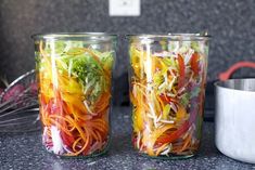 two glass jars filled with different types of vegetables