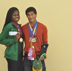 two people standing next to each other holding medals