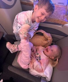 two young children sitting in the back of an airplane with their hands on each other