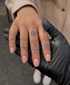 a woman's hand with tattoos on it and a black glove holding her arm