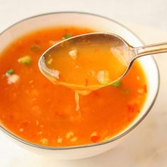 a spoon is full of soup in a bowl