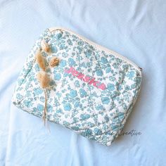 a blue and white flowered bag with some feathers on it