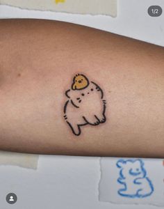 a small tattoo on the arm of a person with a teddy bear in it's hat