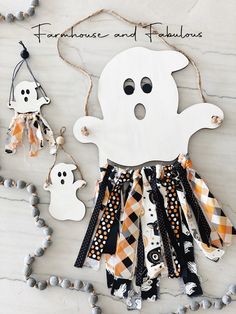 a white wooden ghost hanging from a string with other halloween decorations around it on a marble surface