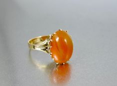 Fabulous antique Victorian era 14K yellow gold Carnelian Agate Ring with a gorgeous oval shaped open back cabochon with ornate dog tooth prongs.  Open back setting allows the light the come through emphasizing the beautiful color and glow of the stone! Split shoulders are engraved with a raised design with smooth band at the back.  No hallmarks noted.  Acid tests and guaranteed 14K.  A stunning ring to add to your antique jewelry wardrobe! Ring is a size 8.   Feel free to contact me with any que August Birthstone Ring, Orange Ring, December Birthstone Ring, Fall Rings, Carnelian Agate, Jewelry Wardrobe, Oyster Bay, Carnelian Ring, Cameo Ring