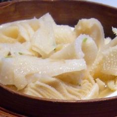 a wooden bowl filled with dumplings on top of a table