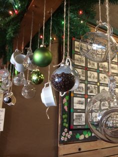 christmas ornaments hanging from the ceiling in front of a wall with pictures and lights on it