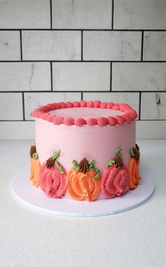 a pink frosted cake decorated with pumpkins