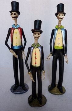 three skeleton figurines are standing next to each other wearing top hats and tails