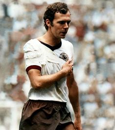 a black and white photo of a soccer player holding his hand on his chest while looking down at the ball