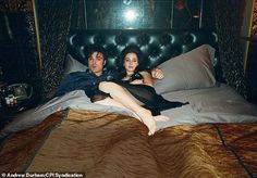 two people laying on a bed in a dark room