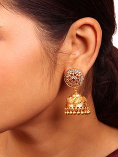 This timeless and classic traditional Kamalika Jhumka exemplifies intricate craftsmanship and detailed design. Its stud section displays a round flower design, embellished with the graceful beauty of white zircon stones, and at the center of the motif, vibrant red and green semi-precious stones. Crafted from 925 sterling silver and polished to a lustrous gold finish. Available in two different colors:  Red and white stones, Green and white stones. Please refer to the pictures of the jewelry worn Traditional Silver Jhumkas For Reception, Heavy Chandbalis For Reception, Elegant Jhumkas With Tilla Details, Traditional Yellow Gold Jhumkas For Wedding, Elegant Tilla Jhumkas, Festive Yellow Gold Hand-set Jhumkas, Elegant Round Tilla Bridal Earrings, Yellow Gold Round Meenakari Jhumkas, Silver Jhumkas With Intricate American Diamond Design