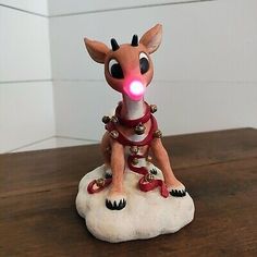 a small figurine sitting on top of a wooden table with a light in it's mouth