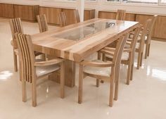 a table and chairs in a room with large windows on the wall, along with wooden cabinets