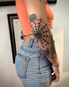 a woman with a spider web tattoo on her lower arm and back half - sleeve