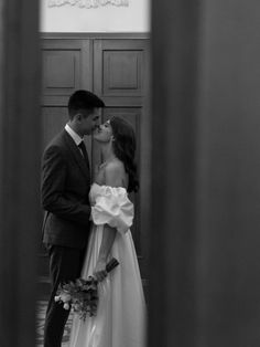 a bride and groom kissing in front of a door