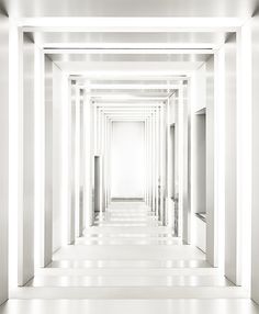 an empty hallway with white walls and columns