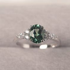 * The delicate ring displays lab green sapphire as main stone. The cluster side stones make the ring similar to the blooming flower . For who wearing this special & delicate ring, will shine like a goddess. ◆ Production Description: Main stone Type: Lab Green Sapphire Main Stone Shape: Oval Cut Main Stone Size: 6*8mm (1.75ct) Side stone: CZ Metal: 925 Sterling silver - Other options available in the drop down menu ◆ Customization: √Free for Add Engraving √Other Metal Type Available √Other Ge Green Sapphire Ring With Accent Stones For Promise, Green Sapphire Promise Ring With Accent Stones, Green Oval Sapphire Ring With Center Stone, Silver Oval Emerald Ring For Proposal, Oval Silver Emerald Ring For Proposal, Oval Sapphire Ring May Birthstone Fine Jewelry, Green Sapphire Diamond Ring For Promise, Green Sapphire Diamond Promise Ring, Green Oval Sapphire Promise Ring