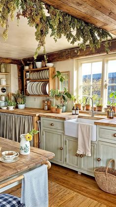 a kitchen filled with lots of wooden furniture and plants hanging from the ceiling over the sink