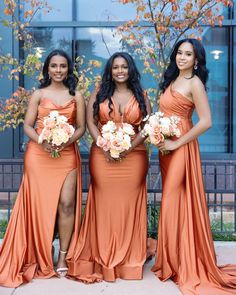 three bridesmaids in orange dresses posing for the camera with their bridal bouquets