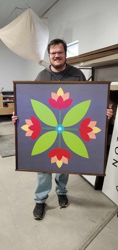 a man holding up a painting with flowers on it