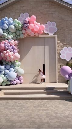 a woman standing in front of a building with balloons all over the entrance and door