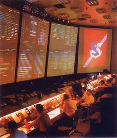 people sitting at tables in front of large screens