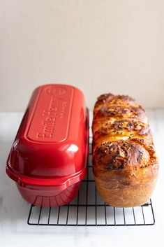 two loaves of bread sitting on top of a rack next to a red container