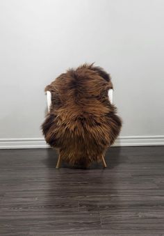 a furry chair sitting on top of a hard wood floor next to a white wall