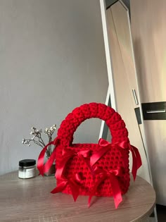 a red knitted basket sitting on top of a wooden table