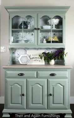 a green china cabinet with flowers in it