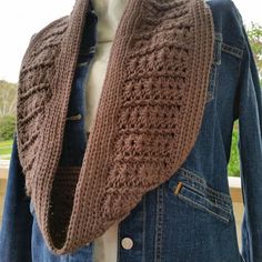 a brown knitted scarf hanging from a mannequin's dummy wearing a denim jacket