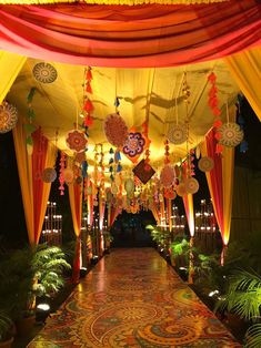 an elaborately decorated walkway is lit up with lights and hanging decorations on the ceiling