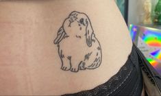 a small rabbit tattoo on the side of a woman's stomach