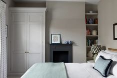 a white bed sitting next to a book shelf in a bedroom