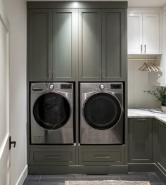 a washer and dryer in a small laundry room with gray cabinets, marble counter tops