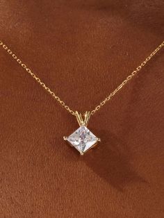 a gold necklace with a princess cut diamond