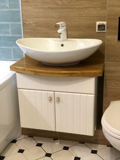 a white sink sitting on top of a wooden counter next to a toilet and bathtub