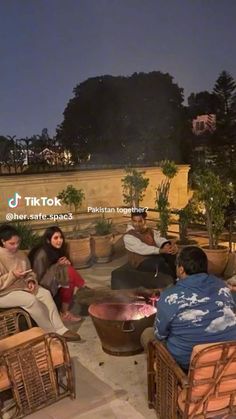 several people sitting around a fire pit at night