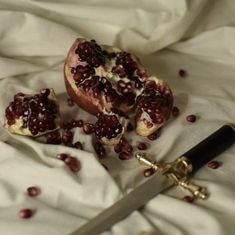 pomegranates are cut into pieces on a white sheet with a knife