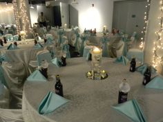 a banquet room set up with blue and white tablecloths, champagne bottles and candles